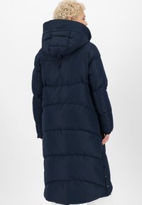 Lungo cappotto imbottito blu navy con cappuccio, caratterizzato da un design trapuntato, dettagli con bottoni a pressione e una vestibilità comoda, realizzato in un materiale liscio e resistente all'acqua.