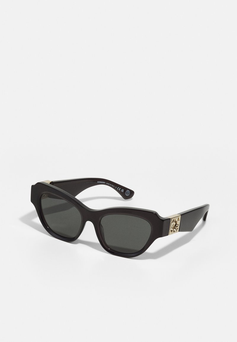Gafas de sol de plástico negro con lentes oscuros, montura angular y acento de logo dorado en el lateral. Textura suave y diseño minimalista.