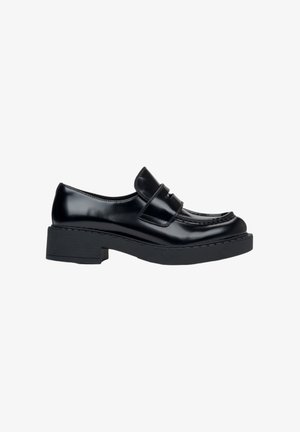 Black leather loafers with a chunky heel, featuring a stitched design and a midsole accent. Smooth texture and classic silhouette.