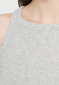 Γκρι ριμπαριστό αμάνικο τοπ με ψηλό λαιμό, που διαθέτει λεία υφή και διακριτική λεπτομέρεια ραφής κατά μήκος του γιακά.