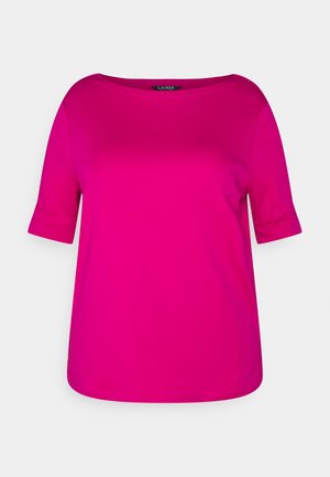 Haut court à manches courtes rose vif pour femme avec un col rond et des manches retroussées sur un fond clair uni.