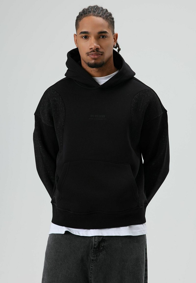 Zwarte hoodie gemaakt van een katoenmix met een grote voorzak, getextureerde stofaccenten op de schouders en een capuchon met trekkoord.