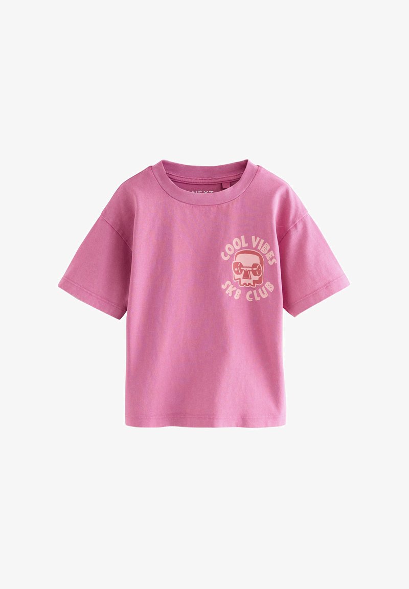 Rožinė medvilninė marškinėliai su trumpomis rankovėmis, ant kurių yra tekstas "COOL VIBES SK8 CLUB" ir grafika su kaukolės dizainu kairėje krūtinės pusėje.
