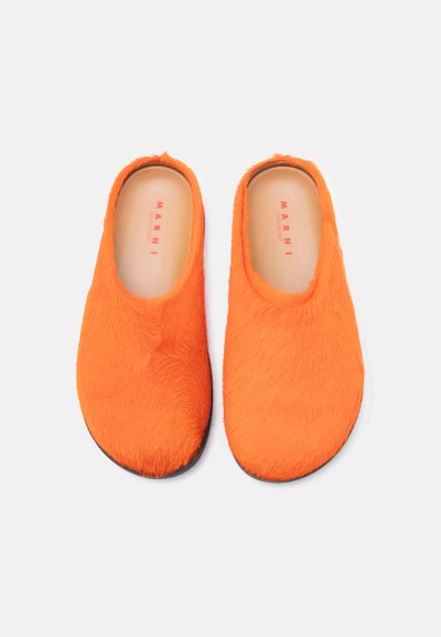 Chaussures oranges à enfiler en fausse fourrure douce, présentant un design lisse et arrondi avec une semelle noire. Logo Marni en rouge sur la semelle intérieure.