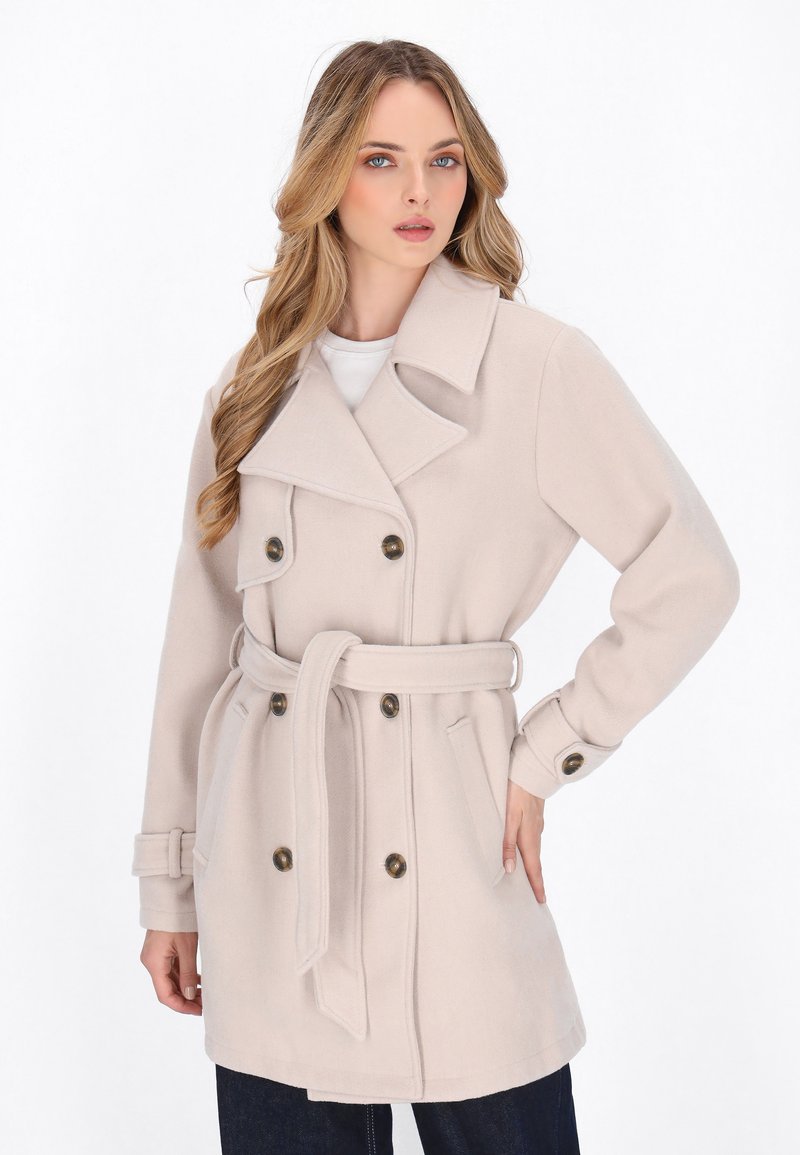 Beige uldblandingsfrakke med dobbeltradet design, stort krave, belagt talje og metalknapper. Lange ærmer med knapmanchetter.