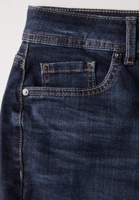Jeans de mezclilla azul oscuro con un corte clásico, costuras visibles en un color marrón claro en contraste y un pequeño bolsillo trasero con un botón metálico.