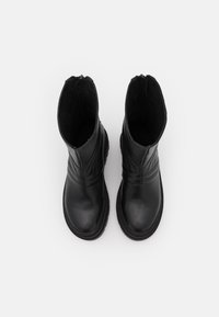 Černé kožené kotníkové boty s kulatou špičkou, texturovaným detailem na svršku a masivní podrážkou; vnitřek podšitý měkkou tkaninou.