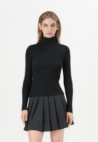 Must mustriba turtleneck-i särk pikkade varrukatega, kombineeritud volditud halli seelikuga. Sile tekstuur ja läbinisti istuv disain.