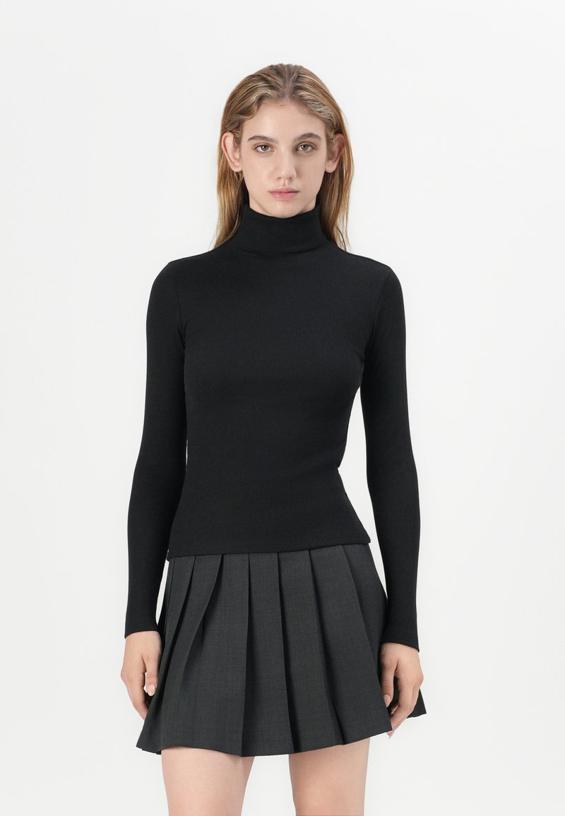 Must mustriba turtleneck-i särk pikkade varrukatega, kombineeritud volditud halli seelikuga. Sile tekstuur ja läbinisti istuv disain.