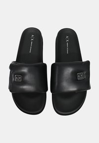 Infradito nere con tomaia in sintetico morbido, fascia ampia e logo in rilievo. Suola piatta, design minimalista, adatte per un look casual.
