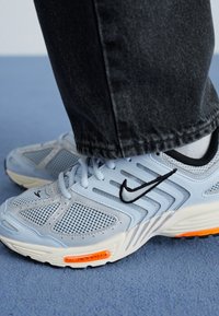 Nike bėgimo batai šviesiai mėlynos spalvos tinklelyje su juodais akcentais, su balta tarpine ir ryškiai oranžiniais akcentais ant pado.
