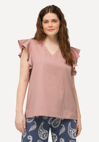Lyserød bluse med korte ærmer og volangdetaljer, V-hals-design, let stof, kombineret med navy bukser med et hvidt paisley-mønster.