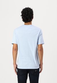 Camiseta de manga corta azul claro, hecha de un material suave, con cuello redondo y una textura lisa con un diseño simple.