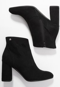 Botines de ante negro con un alto tacón cuadrado, que cuentan con un zipper lateral y un acento plateado cerca de la parte superior. Textura suave y diseño elegante.