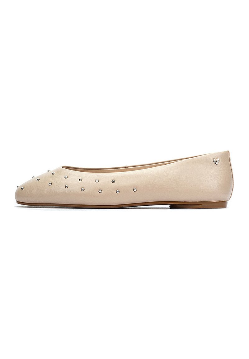 Bailarinas de cuero color beige claro con tachuelas plateadas en la zona de los dedos; forma redondeada, textura suave y un pequeño logo en el talón.