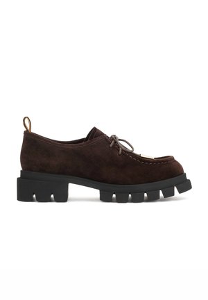 Chaussure en daim marron foncé à lacets avec semelle crantée épaisse noire et languette au talon, montrée de profil sur fond blanc.
