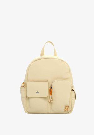 Beżowy plecak z nylonu o zaokrąglonym kształcie, wyposażony w przednią kieszeń, pomarańczowe suwaki oraz dwie boczne kieszenie na dodatkowe przechowywanie.