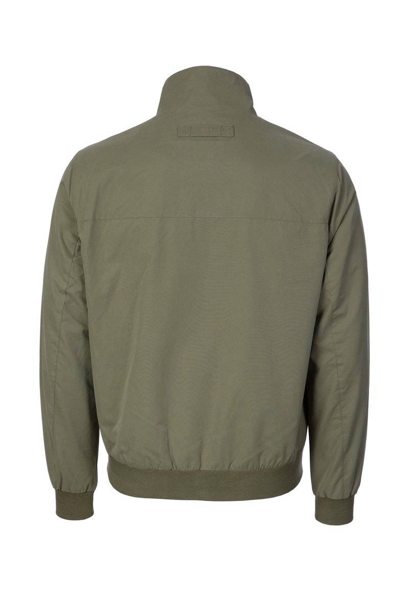 Giacca bomber da uomo verde oliva con colletto alto, polsini ed elastico in vita, vista da dietro su sfondo bianco.