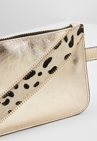 Clutch metallica dorata con dettagli in stampa leopardata nera, caratterizzato da una texture liscia, design diagonale e chiusura con zip.