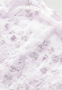 Material lila cu broderie florală intricate, paiete și mărgele, punând în evidență o textură delicată și un design stratificat.