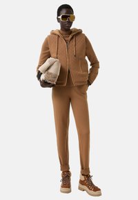 Brown knit ensemble featuring a zip-up vest with textured detail, matching trousers, and chunky brown sneakers with white soles.