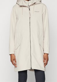 Parka imperméable beige avec une capuche, fermeture zippée à l'avant, deux poches latérales et cordons de serrage réglables. Tissu lisse avec une coupe décontractée.