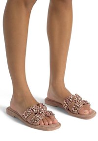Sandales à glissière roses avec des brides agrémentées de pierres précieuses et de perles, texture en suède doux et semelle plate pour le confort.