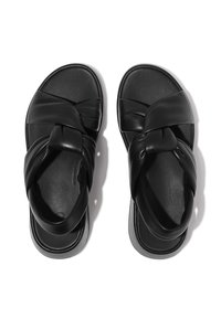 Svarta sandaler med ett crossoverremdesign i slätt läder, med en segmenterad sula och minimalistisk form.