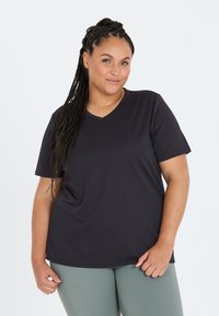 Mørkeblå kortærmet T-shirt med V-udskæring, lavet af et glat, strækbart stof, parret med lysegrønne tætsiddende leggings.