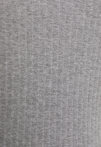 Gros plan sur un tissu en maille côtelée gris montrant des lignes texturées verticales et une surface de matériau douce.