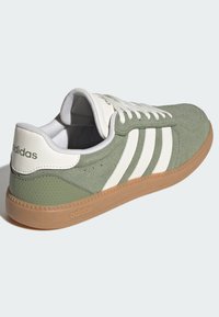 Zeleni antilop tenisica s bijelim prugama, gumenim potplatom, podstavljenim ovratnikom i vezicama. Teksturirani detalji i zaštitni znak na peti.