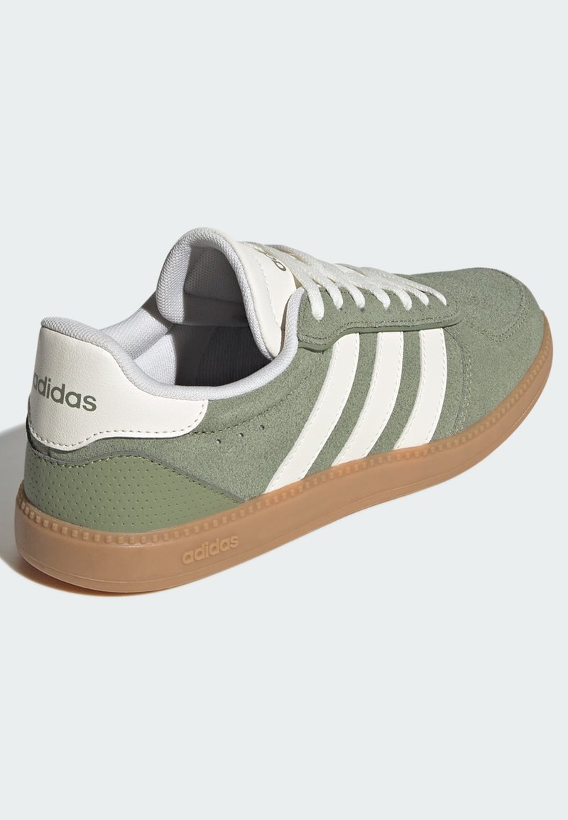 Grüner Veloursledersneaker mit weißen Streifen, gummierter Sohle, gepolstertem Schaft und Schnürsenkeln. Strukturierte Details und Markenkennzeichnung an der Ferse.