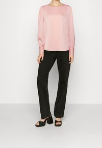 Pink satin blouse with puffed long sleeves, paired with black straight-leg jeans and black platform sandals. Simple round neckline, no patterns.