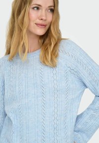 Pull bleu clair en maille avec des motifs à rayures verticales et des détails en dentelle, doté d'un col rond et de manches longues.