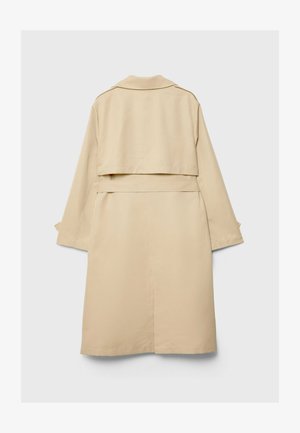 Trench coat beige con orlo posteriore corto, maniche lunghe e cintura. Realizzato in tessuto morbido, presenta un colletto a punte e fessure laterali.