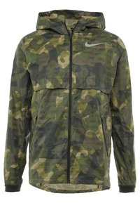 Groene en bruine camouflage Nike-jas met capuchon, frontale rits, ritszakken en subtiel "Just Do It" tekstpatroon.