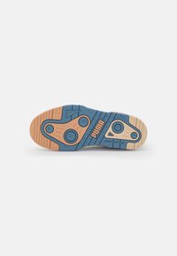 Shoe sole with a blue and tan color scheme. Features circular accents, textured traction patterns, and a prominent logo.