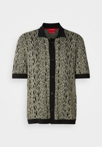 Short-sleeve knitted shirt in green and black with a bold, textured snake-like pattern. Features a black collar and front button closure.