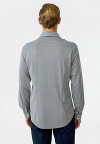 Koolgrijze longsleeve shirt met een puntkraag, knoopmanchetten en een rechte zoom. Glad stof met een subtiele textuur.