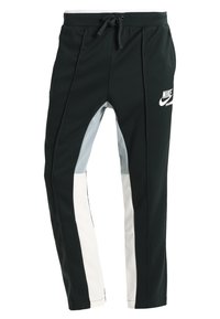 Svarta sportbyxor med grå och vita sidopaneler. Har en dragsko i midjan och en vit Nike-logotyp på framsidan.