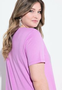 Rosa kortärmad t-shirt med en mjuk tygstruktur. Har en rund halsringning och en subtil ögonfallande design på framsidan.