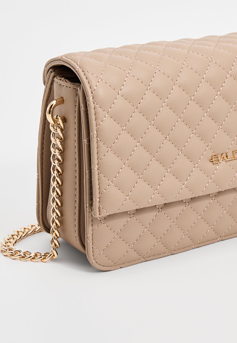 Beige gesteppte Handtasche aus Kunstleder mit einem Goldkettenriemen und einem Frontklappenverschluss. Merkmale sind eine glatte Textur und subtile Steppdetails.