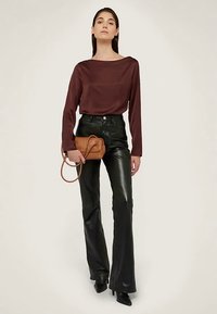 Top marrone a maniche lunghe, pantaloni aderenti in pelle neri, tacchi neri e una piccola borsa marrone. Tessuto liscio, vestibilità casual con vita alta.