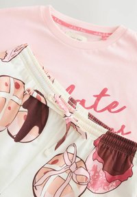 Lyserød bomulds t-shirt med teksten "Make Time" parret med hvide shorts med farverige dessertmotiver og en lyserød snor.