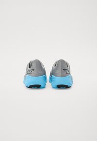 Des chaussures de sport grises avec un dessus texturé, une semelle en caoutchouc bleue et un accent noir au talon. Conçues pour le confort et la performance.