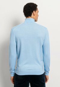 Helles blaues Langarmpullover mit einem Stehkragen, glatter Textur und gerippten Bündchen. Die Rückansicht zeigt die Schulternähte und ein minimalistisches Design.