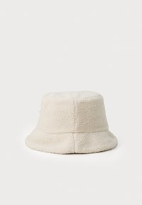 Krémová kšiltovka vyrobená z měkkého, strukturovaného fleece s kulatou korunou a širokým, dolů skloněným kšiltem. Obsahuje švy.