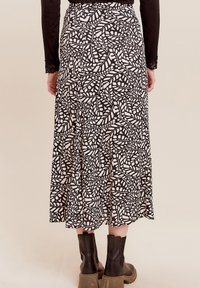 Maxirock in Schwarz und Weiß mit einem Blattmuster; leichtes Material, A-Linie Silhouette, Bund und sichtbare Nahtdetails am Saum.