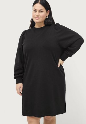 Robe sweat noir avec de longues manches bouffantes, col rond, poches latérales, longueur genoux et tissu doux et texturé.