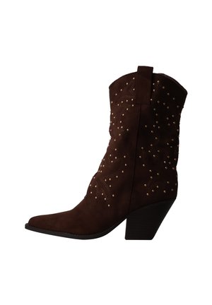 Bottine cowboy en daim brun foncé avec talon empilé et petits clous métalliques ronds formant des motifs décoratifs sur la partie supérieure.